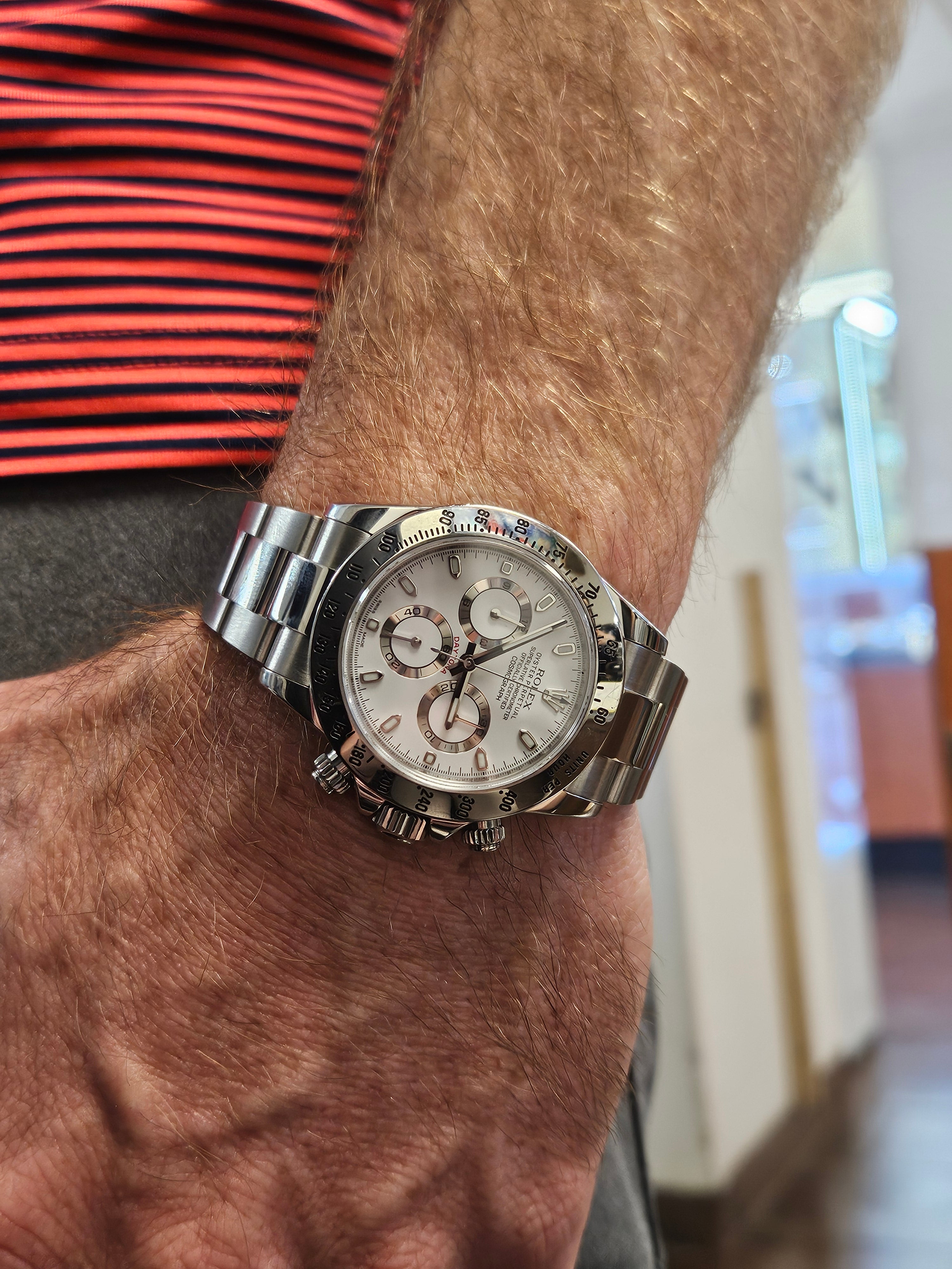 Rolex Daytona stainless steel chronograph watch with white dial worn on wrist.